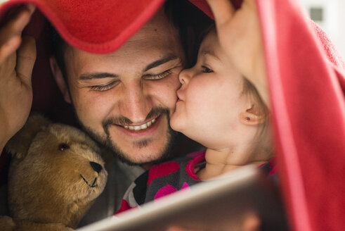 Father and daughter with digital tablet under blanket - UUF003358