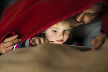 Father and daughter with digital tablet under blanket - UUF003362