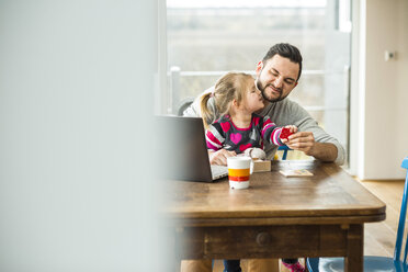 Father and daughter with laptop and game at wooden table - UUF003399