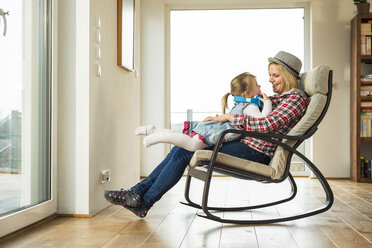 Mother and daughter on rocking chair with headphones - UUF003380