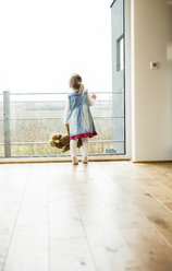 Mädchen hält Teddy und schaut aus dem Fenster - UUF003385