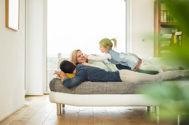 Family lying on couch on top of each other - UUF003391