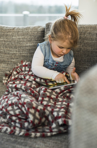 Mädchen auf Couch mit digitalem Tablet, lizenzfreies Stockfoto