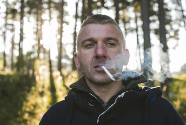 Bulgaria, man smoking cigarette in the forest - DEGF000219