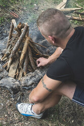 Mann zündet ein Feuer auf einer Wiese an - DEGF000231