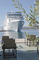 Greece, olive twig with cruise liner moored at harbour in the background - DEGF000147