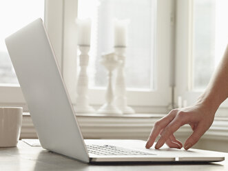 Deutschland, Köln, Hand tippt auf Tastatur von Laptop - RHF000487