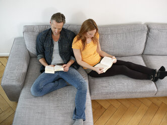 Mature man with adult daughter reading on sofa - RHF000503