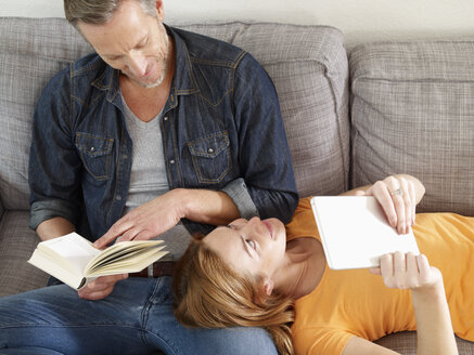 Älterer Mann mit erwachsener Tochter liest auf dem Sofa - RHF000506