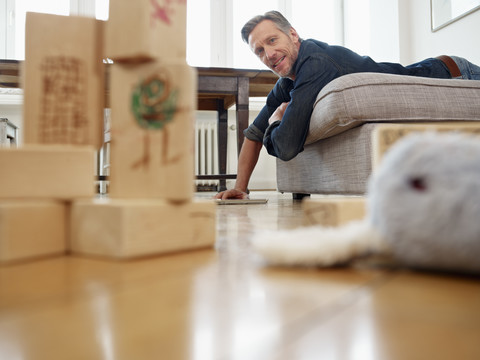 Älterer Mann auf dem Sofa liegend mit digitalem Tablet, lizenzfreies Stockfoto