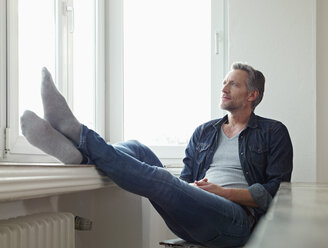 Deutschland, Köln, Älterer Mann sitzt am Fenster und schaut hinaus - RHF000514