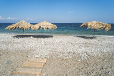 Greece, Peloponnese, three straw umbrellas on the beach - DEGF000193