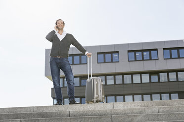 Telephoning businessman standing on stairs with his suitcase - PDF000769