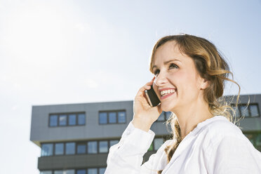 Lächelnde Geschäftsfrau beim Telefonieren mit ihrem Smartphone - PDF000771