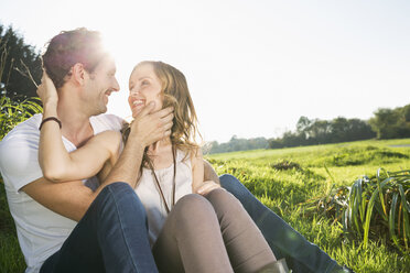 Happy couple face to face sitting on a meadow - PDF000798