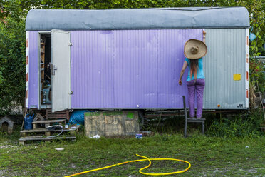 Woman painting trailer in garden - TCF004567