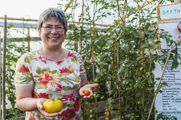 Frau im Gewächshaus mit roter und gelber Tomate - TCF004571