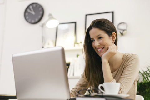 Junge Unternehmerin bei der Arbeit mit Laptop im Home Office, lizenzfreies Stockfoto