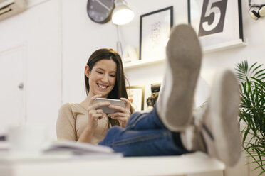 Junge Unternehmerin, die sich mit ihrem Smartphone im Büro ausruht - EBSF000445