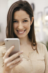 Porträt einer jungen Unternehmerin mit Smartphone im Heimbüro - EBSF000454