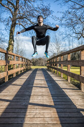 Spain, Gijon, athlete jumping on wooden bridge - MGOF000121