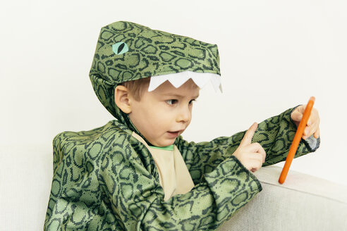 Kleiner Junge im Dinosaurierkostüm sitzt mit Smartphone auf der Couch - MFF001484