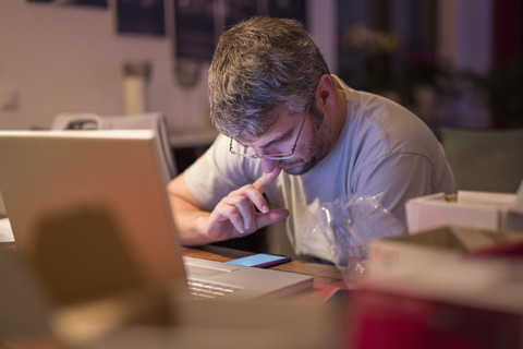 Mann mit Laptop und Smartphone am Schreibtisch, lizenzfreies Stockfoto