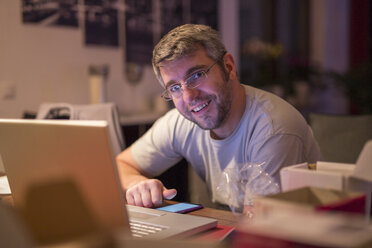 Smiling man with laptop and smartphone at desk - SHKF000250