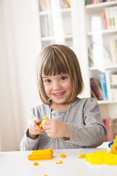 Porträt eines glücklichen kleinen Mädchens, das mit gelber Knetmasse spielt - LVF002866