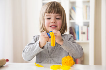 Kleines Mädchen spielt mit gelber Knetmasse - LVF002864