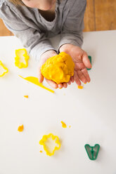 Girl holding yellow modeling clay in hands - LVF002862
