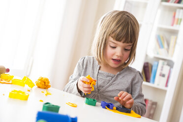 Kleines Mädchen spielt mit gelber Knetmasse - LVF002857