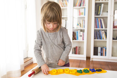 Little girl cutting out yellow modeling clay - LVF002848