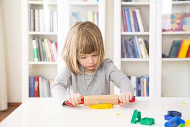 Little girl rolling out yellow modeling clay - LVF002845