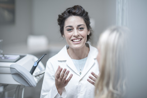 Dentist explaining procedure to patient sitting in dentist's chair stock photo