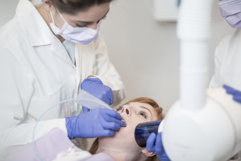 Zahnärztin untersucht die Zähne eines Patienten, lizenzfreies Stockfoto