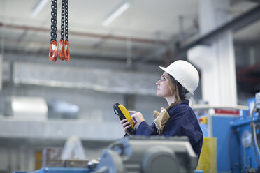 Techniker in der Fabrikhalle, der den Regler für den Haken benutzt - SGF001328