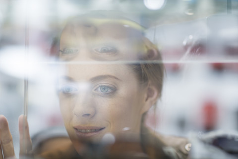 Junge Frau schaut durch ein Schaufenster, lizenzfreies Stockfoto