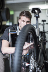 Junger Mann arbeitet in einem Fahrradgeschäft - ZEF005045