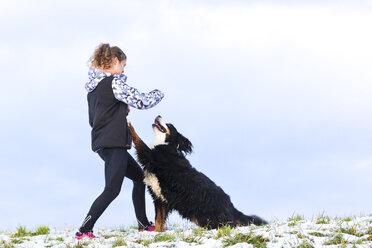 Young woman playing with her Saint Bernard on snow-covered meadow - STSF000698