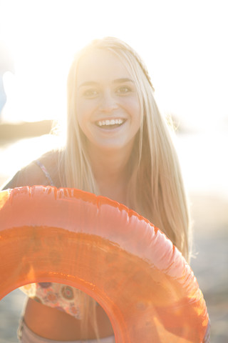 Glückliche junge Frau mit Schwimmreifen am Strand, lizenzfreies Stockfoto