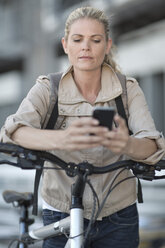 Blonde Frau auf dem Fahrrad mit Mobiltelefon - ZEF004942