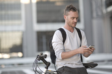 Blone man on bicycle using smart phone - ZEF004944