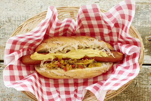 Veganer Hot Dog mit Sauerkraut und Relish auf Serviette im Korb - HAWF000644
