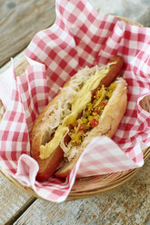 Veganer Hot Dog mit Sauerkraut und Relish auf Serviette im Korb - HAWF000645