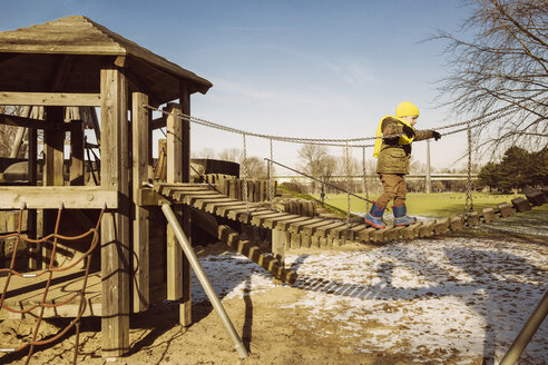 Kleiner Junge läuft auf einem Spielplatz über eine Hängebrücke - MFF001503