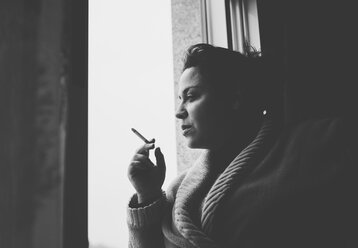 Spanien, Galicien, Naron, Erwachsene Frau raucht am Fenster ihrer Wohnung - RAEF000043
