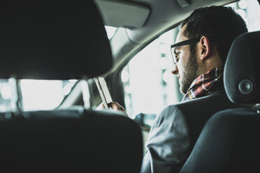 Young businessman in car looking on cell phone - UUF003442