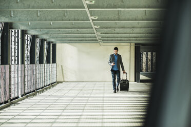 Young businessman walking in car park looking on cell phone - UU003443