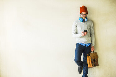 Young man with leather bag looking on cell phone - UUF003451